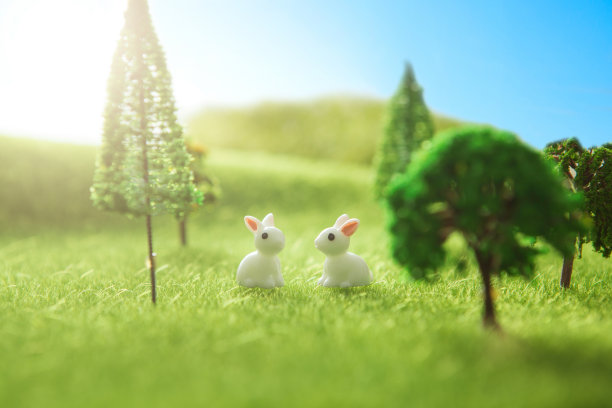 草地上有两个带着复活节彩蛋的兔子玩具。黄色的复活节彩蛋春天草地上有两只兔子和复活节彩蛋。童话故事图片下载