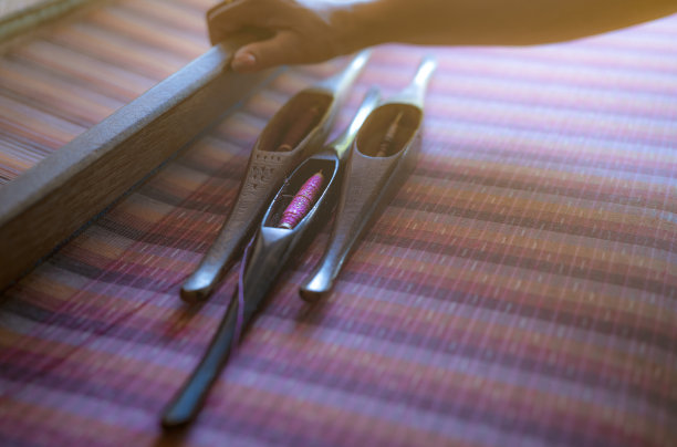 在织布机上工作的妇女，编织手工织物。纺织织造。用传统手工织布机在棉线上织造。泰国的纺织或布料生产。亚洲文化。图片下载