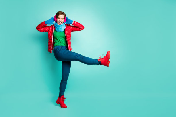 漂亮的女士的全尺寸照片走在街上抬高腿高好玩的调情的心情手在耳朵上穿休闲的红色外套围巾粉红色的耳朵皮手套裤子套头衫手套鞋子孤立的蓝绿色背景图片下载