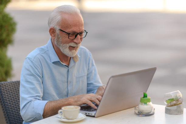 一个老男人坐在外面喝咖啡，用笔记本电脑拍照片图片下载