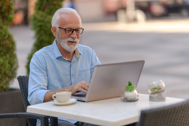 一个老男人坐在外面喝咖啡，用笔记本电脑拍照片图片下载