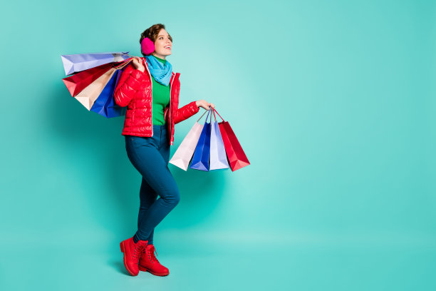 全身的轮廓侧面的照片积极的女孩购物中心客户拿着包看copyspace梦想减价穿绿色的套头衫粉红色的红蓝色的裤子裤子孤立的蓝绿色的背景图片下载