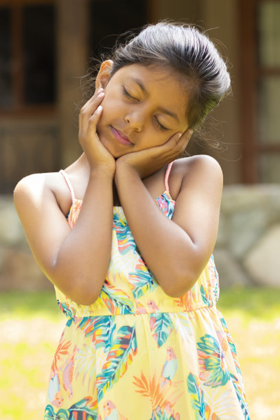 一个棕发小女孩的肖像，手放在脸上图片下载