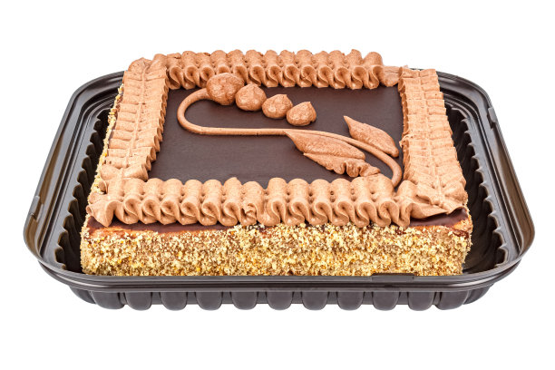 巧克力酥饼，用奶油装饰和花的图案装饰在一个开放的塑料包装上，孤立在白色的背景。前视图图片下载