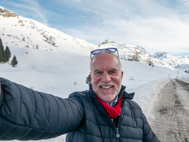 中年男人在雪山背景下自拍；人们在冬季度假图片下载