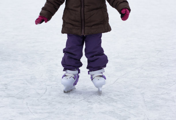 在冬季的溜冰场上的孩子腿上的溜冰鞋的前视图图片下载