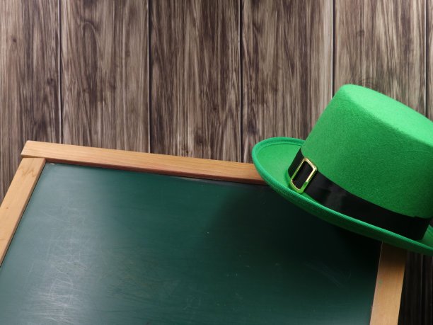 绿色的帽子在黑板和木制背景与复制空间，圣帕特里克日的概念图片下载