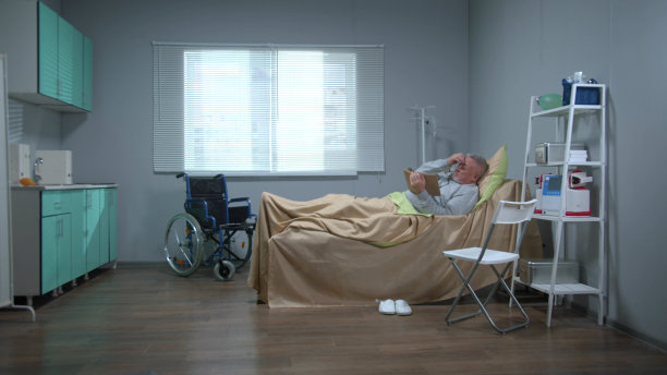 一个男人躺在医院的床上，在平板电脑上看一些东西图片下载