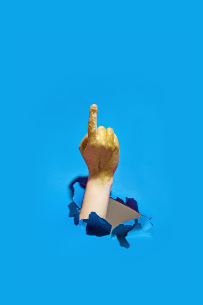 手势男人的手穿过撕破的蓝纸图片下载