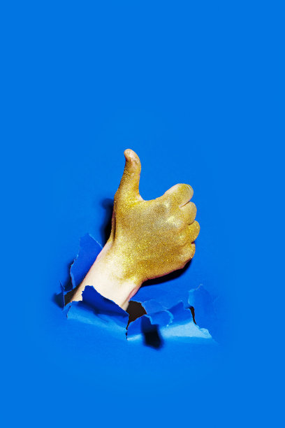 手用金色的闪光打破纸与拇指向上图片下载