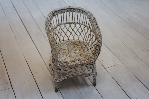 白色木制背景上的一把小柳条椅子图片下载