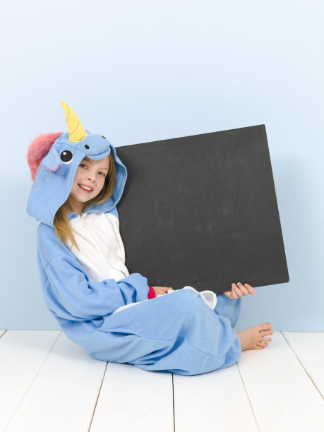 漂亮的金发女孩穿着舒适的蓝色独角兽服装和黑板在摆姿势图片下载