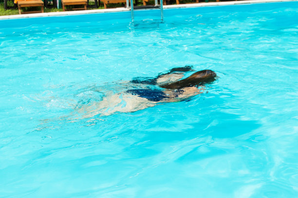 十几岁的年轻女孩在室外游泳池的水下游泳，溅起水花，明亮的阳光，眩光，夏日，娱乐和度假时间图片下载