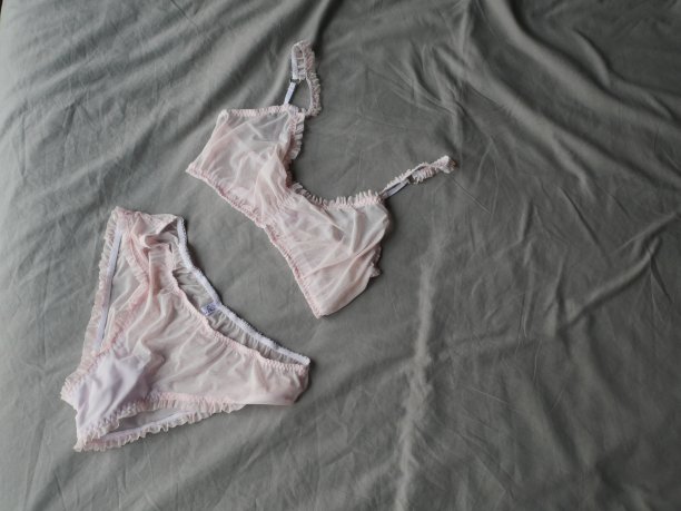 女人的粉色温柔性感内衣躺在灰色的床为背景。内衣礼物图片下载