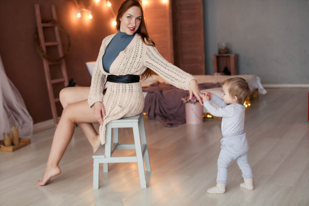 漂亮的年轻女子坐在椅子上，旁边有个婴儿。图片下载