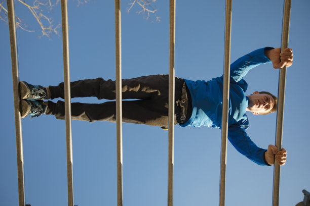 低角度的年轻成年男子做俯卧撑在水平墙酒吧户外-库存照片图片下载