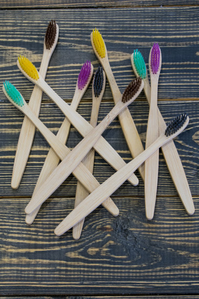 竹制环保牙刷，刷毛鲜艳多彩，木质背景图片下载