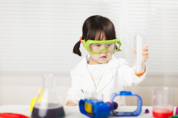 蹒跚学步的女孩在白色背景下扮演科学家的角色图片下载