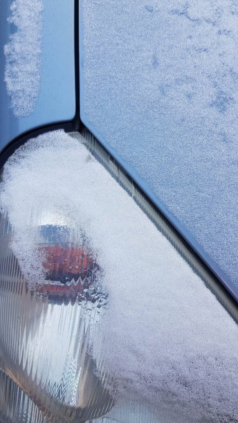 车灯表面特写覆盖着一层薄薄的雪。浅蓝色汽车细节与几何线。带霜皮的三角汽车灯。冬天的背景。寒冷天气工业背景。图片下载
