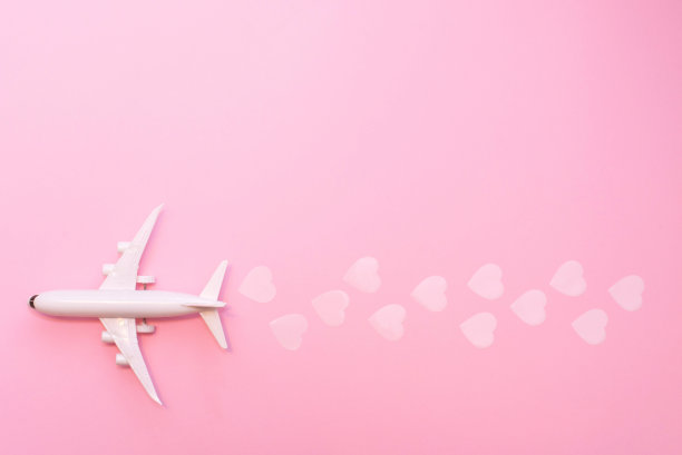 情人节快乐。粉色背景上的白色飞机，还有心形图案图片下载