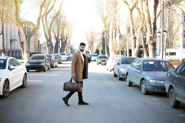 英俊的印度男子走在城市街道上的包。图片下载