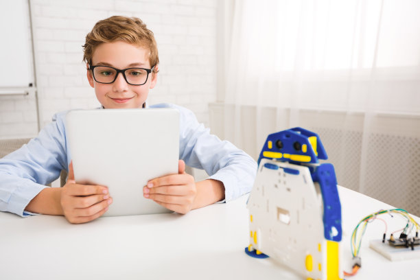男孩控制机器人与平板电脑在stem教育课图片下载