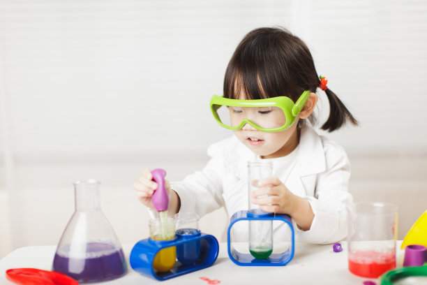 蹒跚学步的女孩在白色背景下扮演科学家的角色图片下载