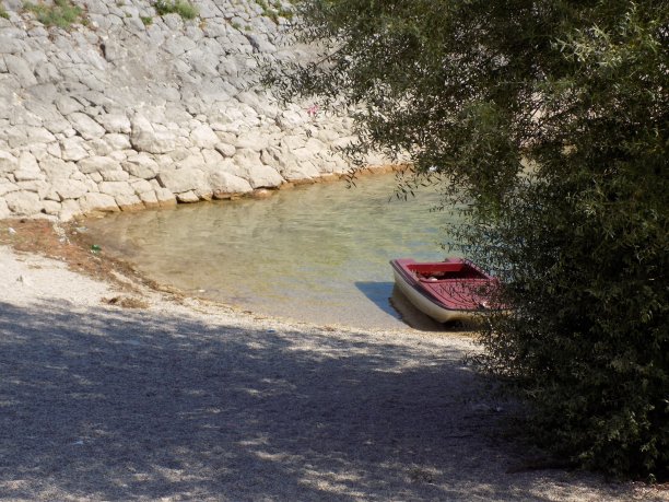一艘塑料小船停泊在多岩石的岸边图片下载