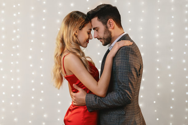 浪漫的情侣触摸额头，拥抱，在灯光背景下一起摆姿势图片下载