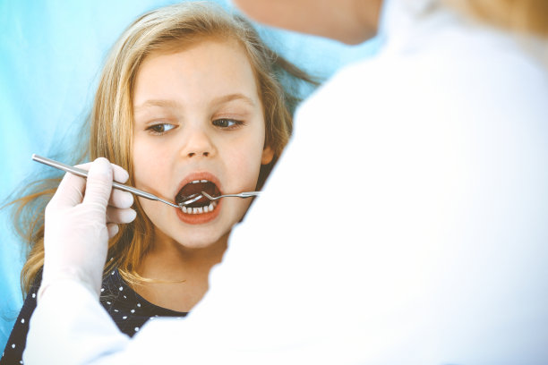 小女孩张大嘴巴坐在牙科椅上接受医生的口腔检查。拜访牙医的办公室。医学概念。健美的照片图片下载