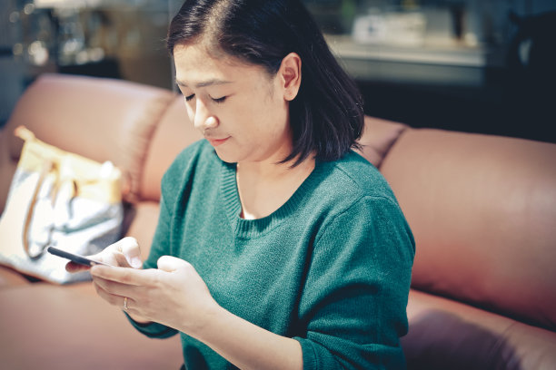 亚洲女性在沙发上使用手机图片下载