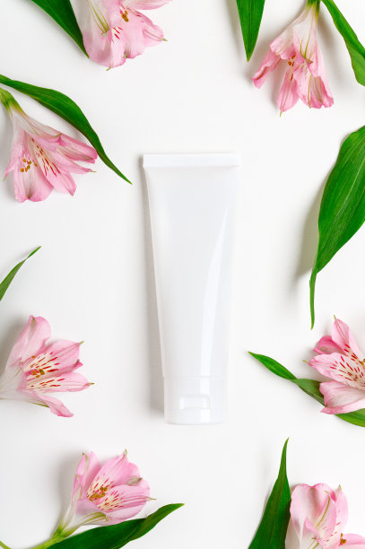 手霜空白管模型上花白色背景。润肤霜，香波，润肤露，香脂，粉色百合花塑料包装。女性护肤产品创意成分图片下载