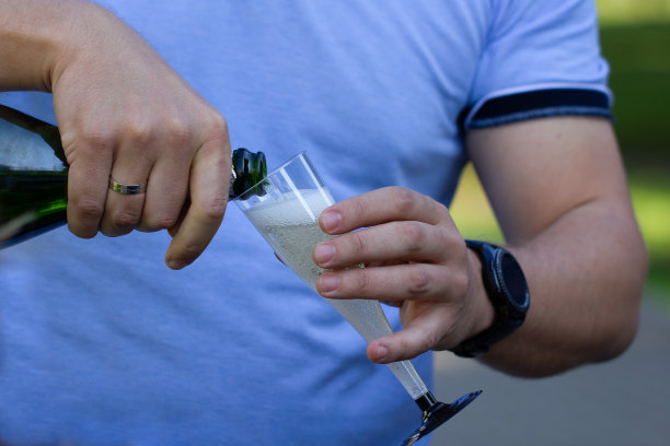 穿着蓝色t恤的男人倒香槟，特写图片下载