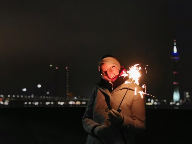 年轻女子在Düsseldorf天际线前的浪漫照片，手里拿着闪闪发光的东西图片下载
