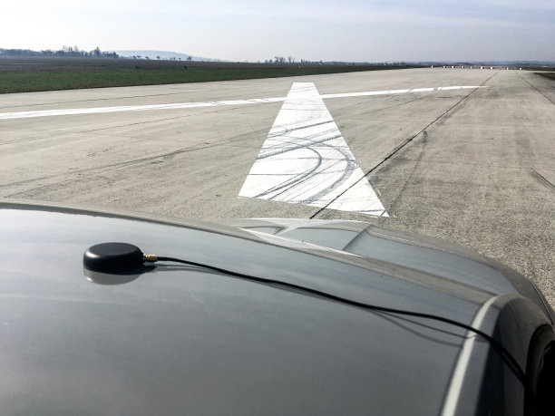 一辆汽车在加速测试前站在机场跑道上的照片。你可以看到屋顶上的GPS天线。图片下载
