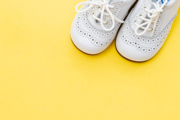 黄色背景上的白色婴儿鞋图片下载