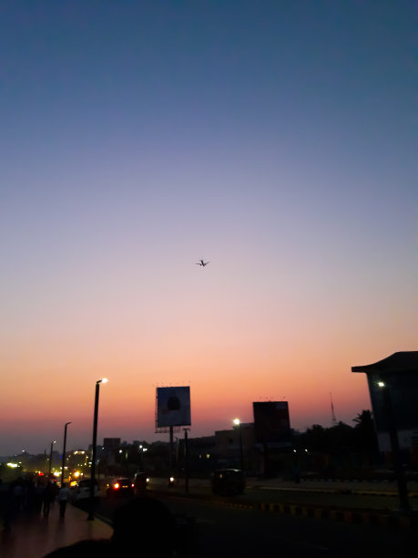 这是在印度海得拉巴的晚上，粉红色的天空中有一架小飞机，钢灯在亮着图片下载