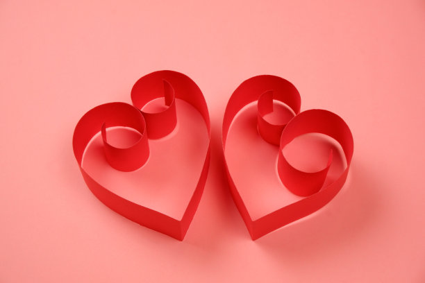 粉色背景上的一对红纸爱心图片下载