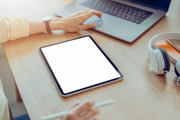 女人手持平板电脑和数字笔与空白拷贝空间屏幕为您的广告。笔记本电脑放在办公室的桌子上。图片下载