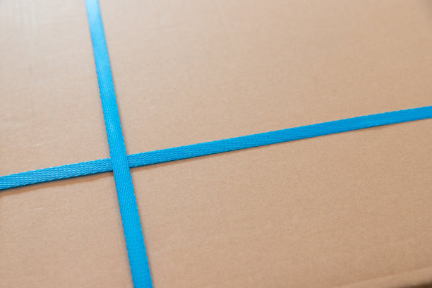 棕色包裹上带蓝色包装带。带塑料皮带扣的货运包裹。图片下载