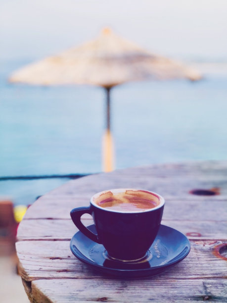 浓缩咖啡放在一张木制圆桌上。背景中的海滩图片下载