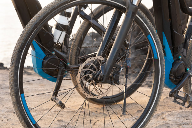 两辆电动自行车停在悬崖上。把注意力放在轮子上。夕阳的光。黑色自行车图片下载
