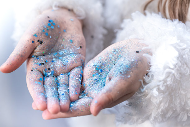 一个穿着蓝色亮片的小女孩的手。图片下载