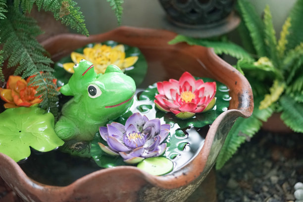 青蛙。青蛙妈妈和她的小青蛙在睡莲池塘里，用陶瓷做的花园装饰青蛙。图片下载