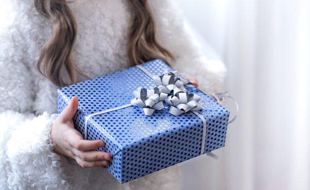 一个小女孩拿着一件蓝色的节日礼物。图片下载