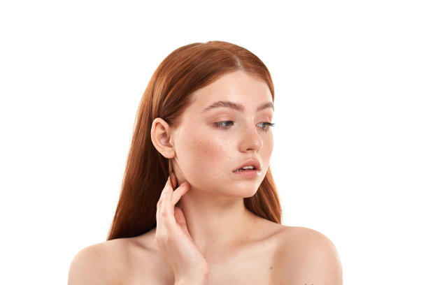 完美的皮肤。近距离的肖像，一个年轻和美丽的红发女孩脸上的雀斑看远，而站在白色的背景图片下载