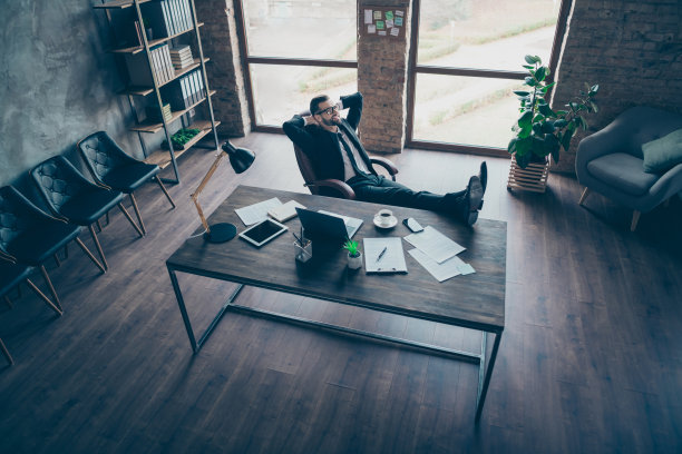 高角度以上视图英俊的商人的个人资料照片放松的腿在桌子上露齿微笑的手在后面的头穿着眼镜黑色运动夹克衬衫长裤领带西装坐在椅子办公室室内图片下载