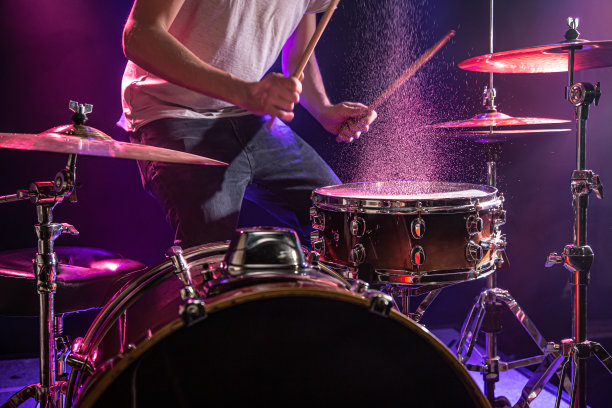 鼓手打鼓。美丽的蓝色和红色背景，与光线。美丽的特效烟雾和灯光。演奏乐器的过程特写照片。图片下载