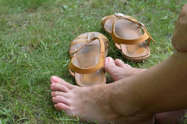 女性的脚赤脚躺在绿色的草地上，夏天穿着鞋子图片下载