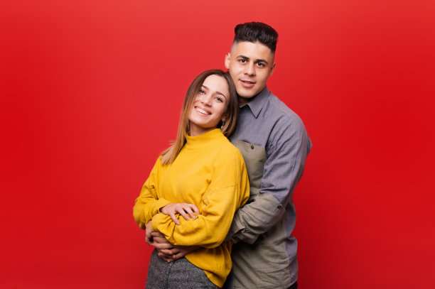 年轻幸福的夫妇拥抱在红色的背景肖像图片下载
